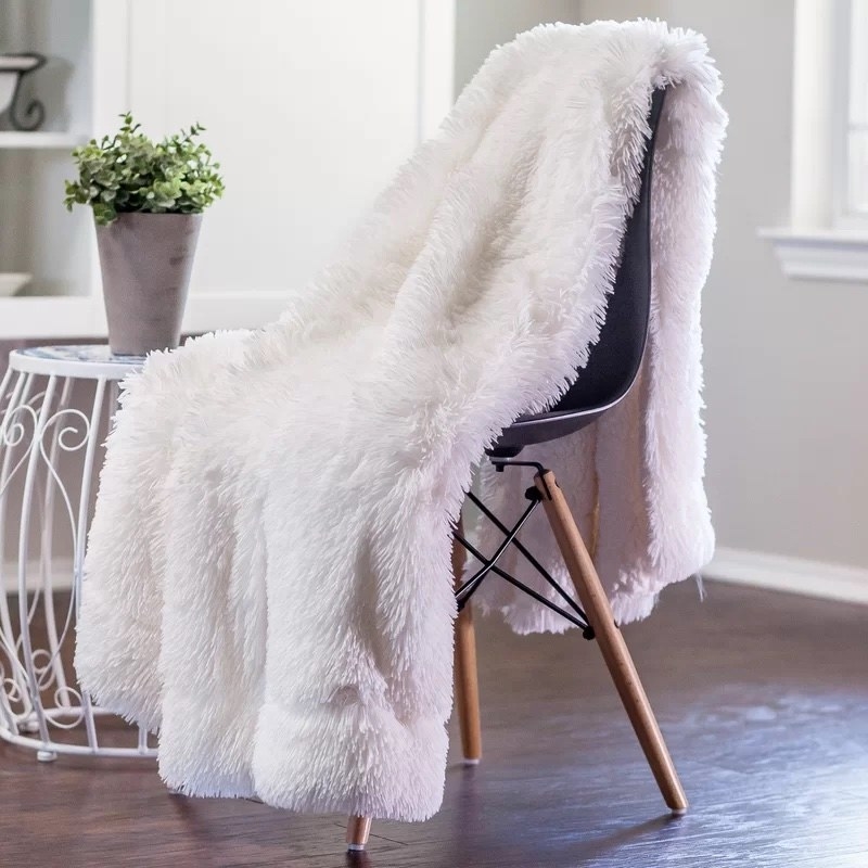 A fluffy white blanket on a black chair