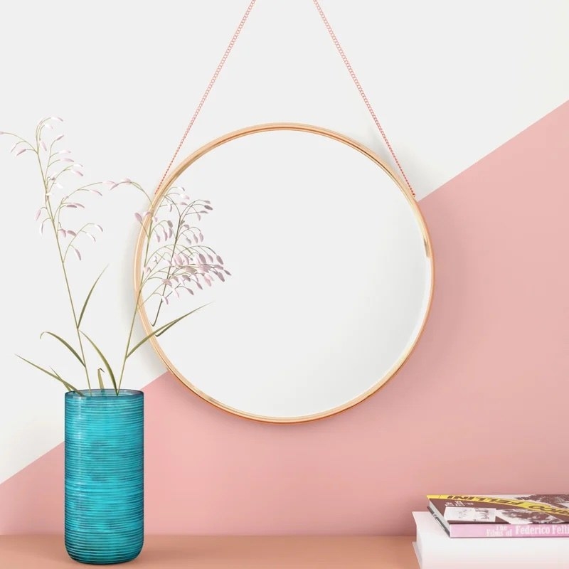A gold mirror on a pink wall