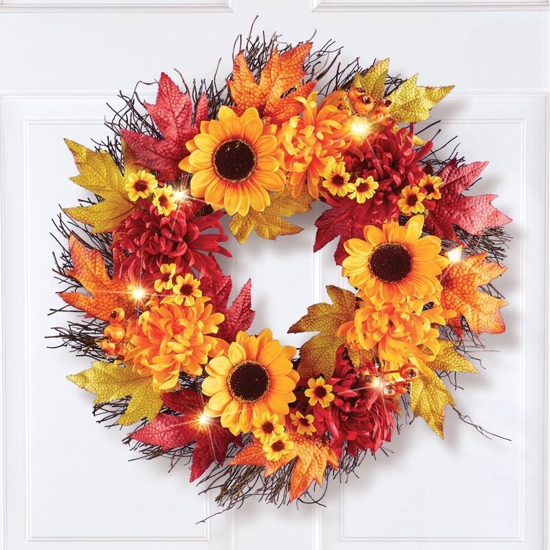 A red, orange and yellow sunflower wreath hanging up on a door