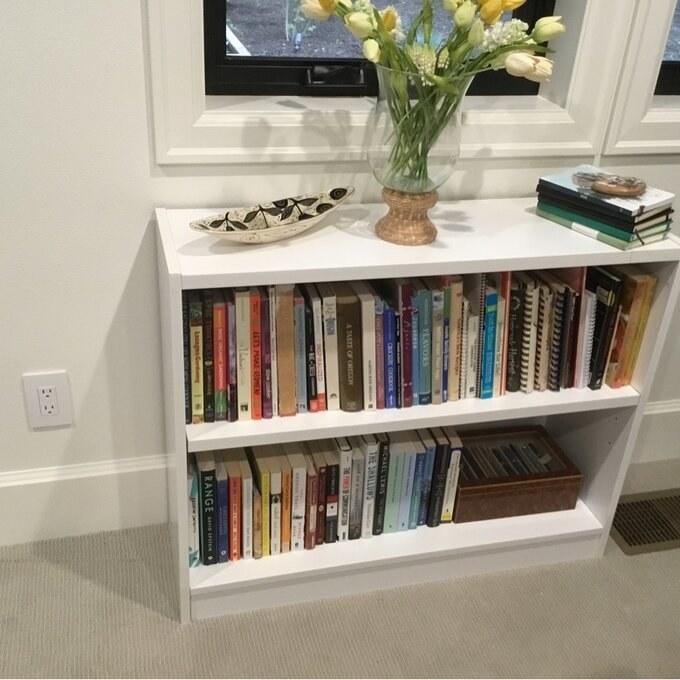 A reviewer&#x27;s photo of the white bookcase filled with books