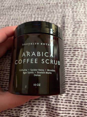 A reviewer holding the coffee scrub product jar
