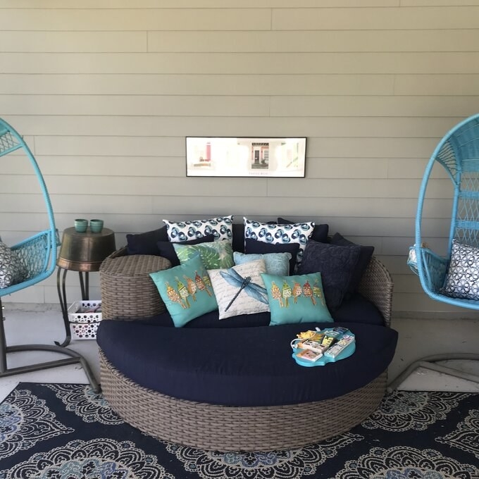A reviewer&#x27;s photo of the navy daybed on her porch with throw pillows
