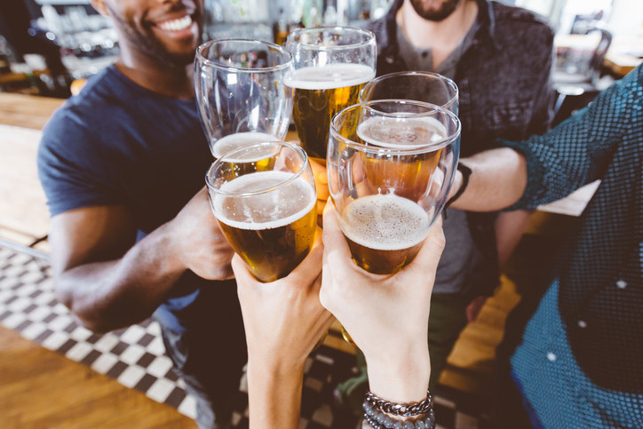 A group of friends clink their glasses of beer