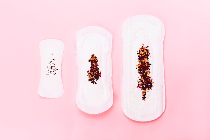 Three sanitary pads in different sizes, all with red glitter in them to signify blood
