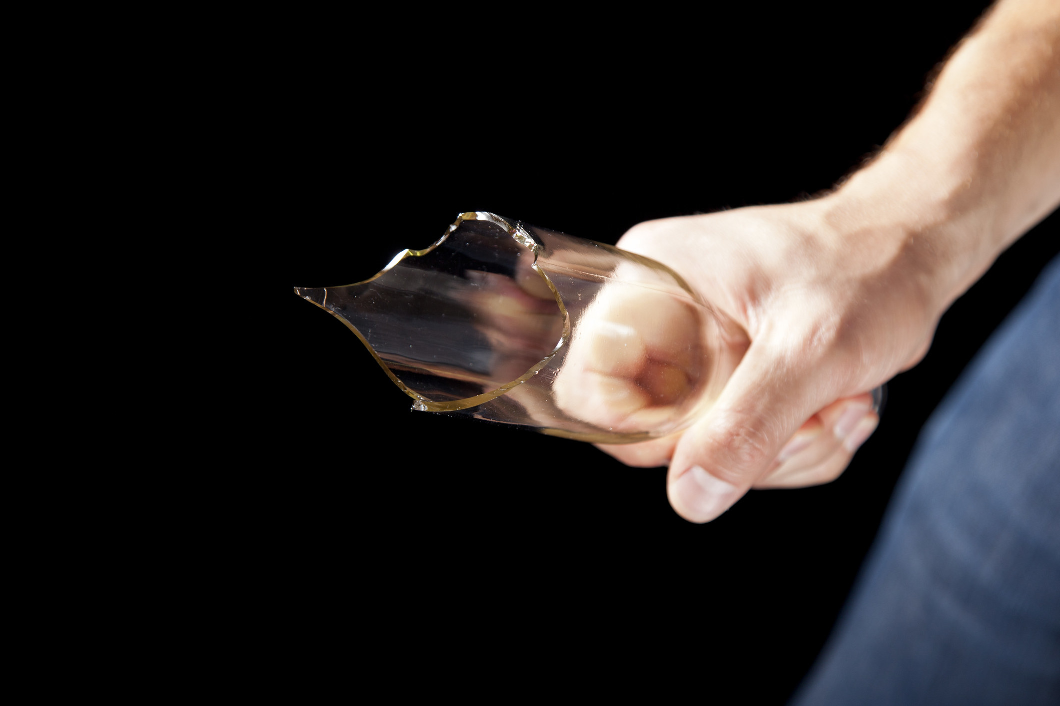 A person holding a broken glass bottle