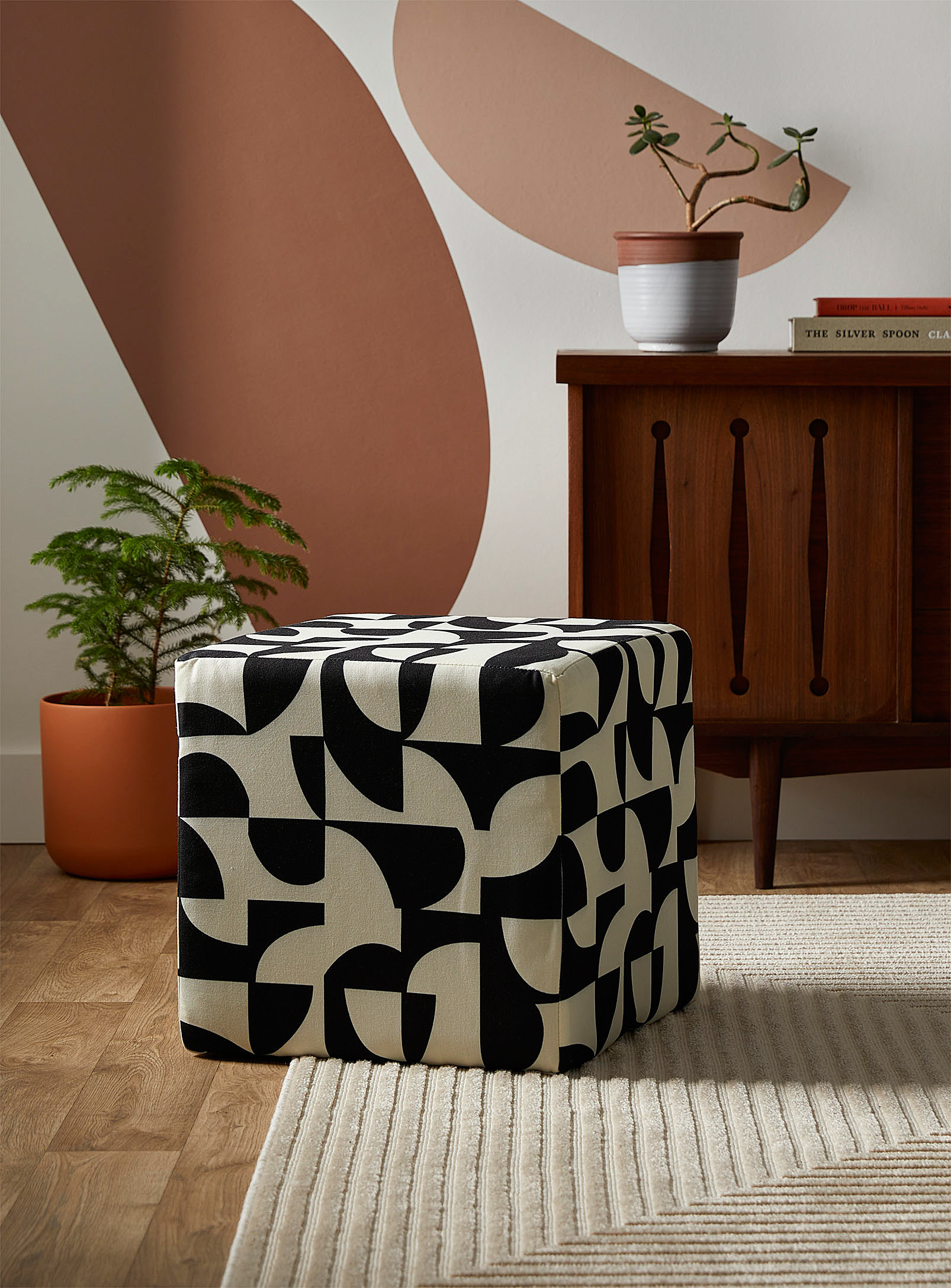 A small cube-shaped ottoman on a rug