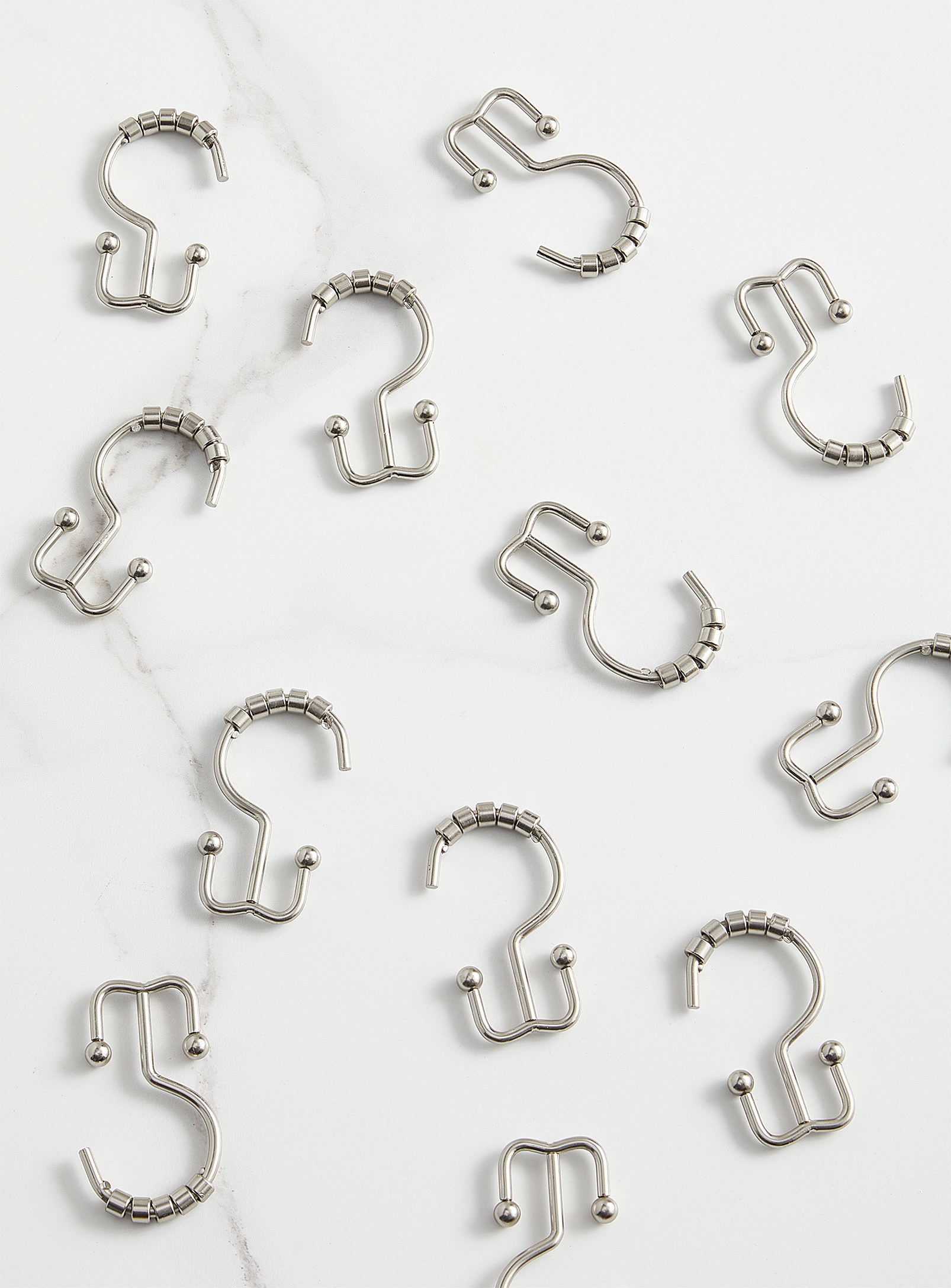 A bunch of shower curtain hooks on a plain background