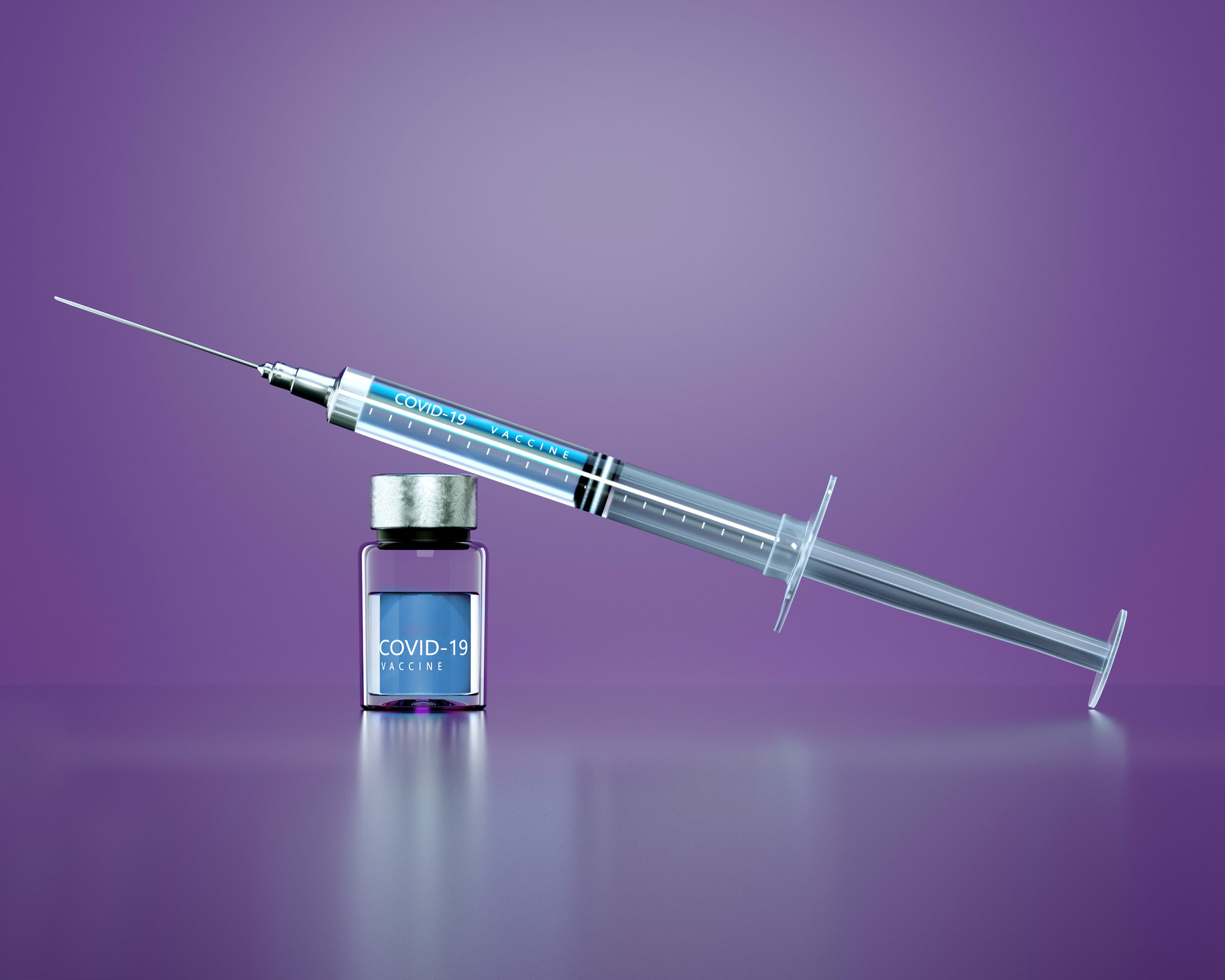A syringe on top of a bottle labeled COVID-19 Vaccine