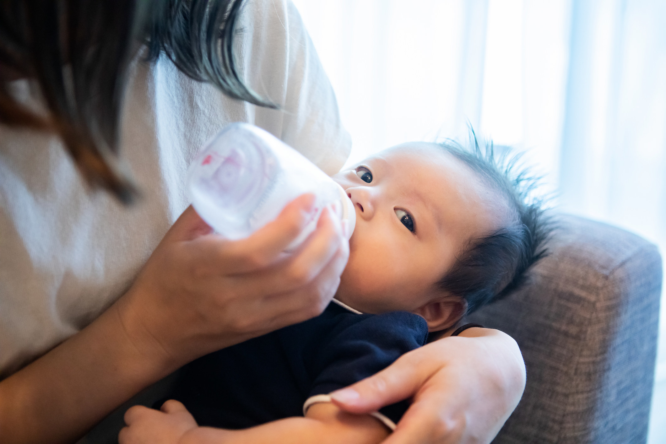A person bottle feeding a baby
