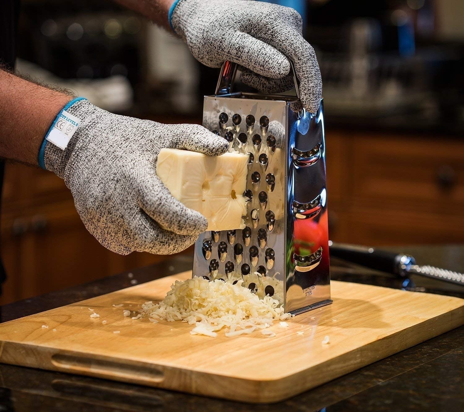 A hand grating cheese with the anti-cut gloves on