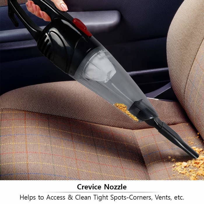 A handheld vacuum cleaner cleaning crumbs off a chair