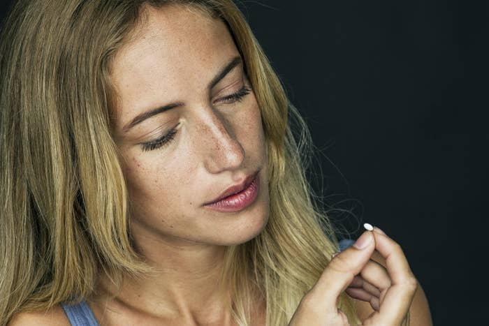 An image of a woman staring at a birth control with a look of thoughtfulness
