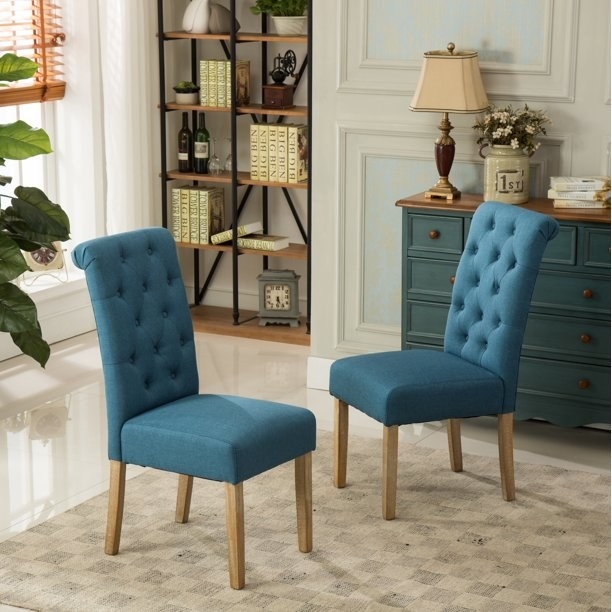 Two teal tufted dining chairs.