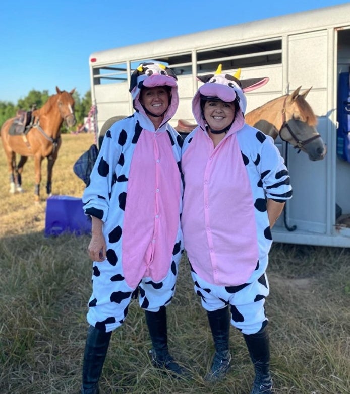 Two women dressed in the cow onesies