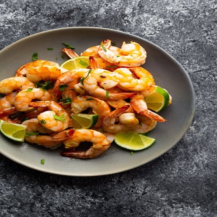 Honey lime shrimp on a plate with lime wedges.