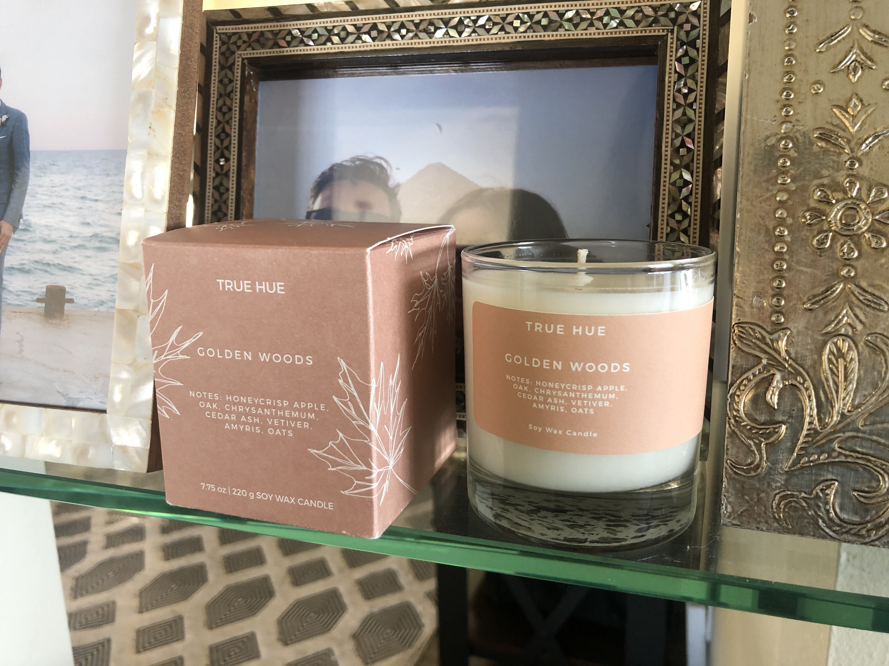 The candle and its packaging is shown on a glass shelf