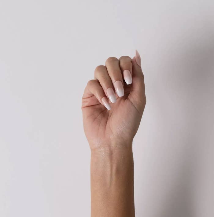 An adult has their hand posed to show their coffin-shaped ombre french tip nails