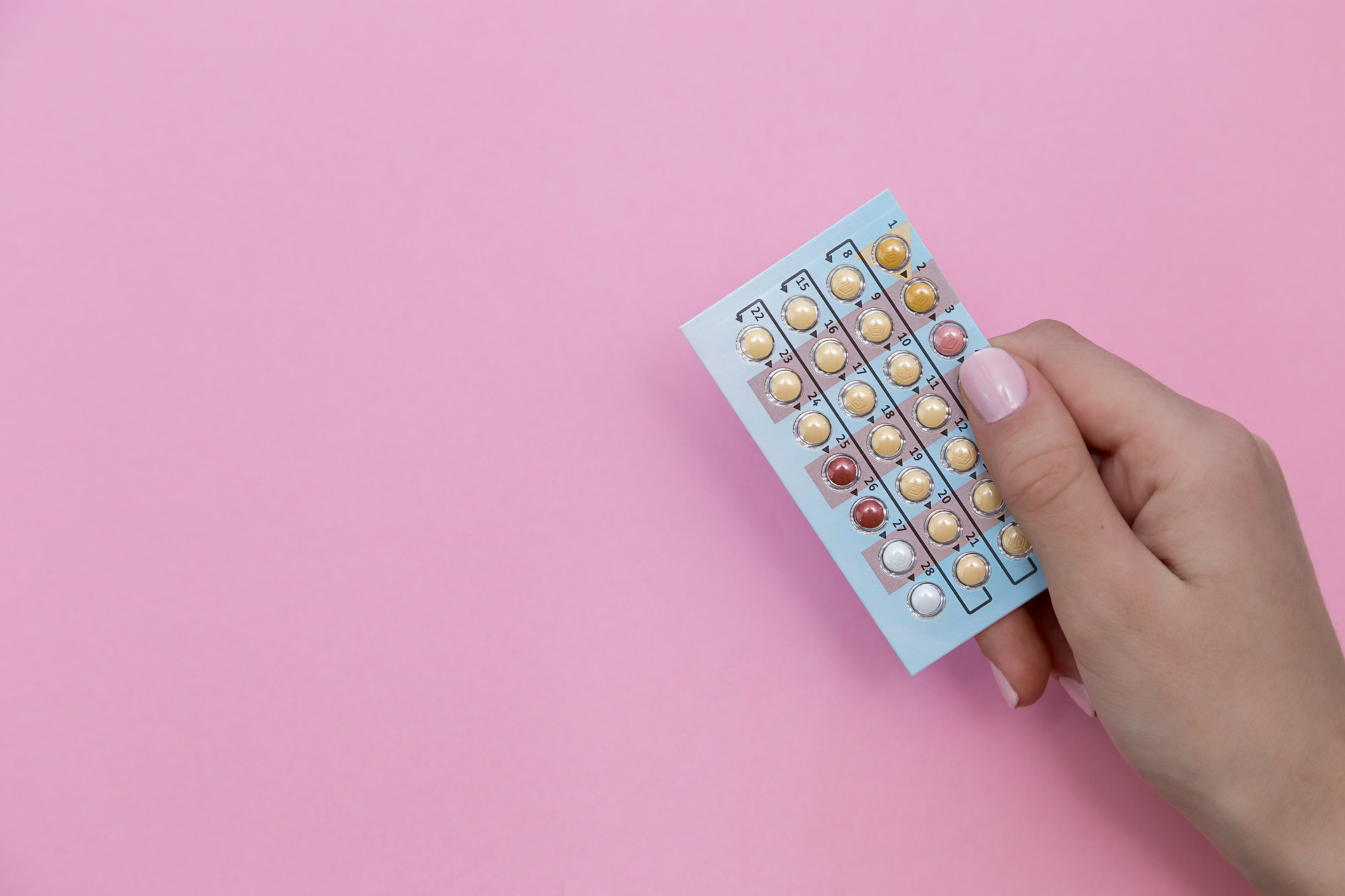 Stock image of a hand holding up a birth control pack
