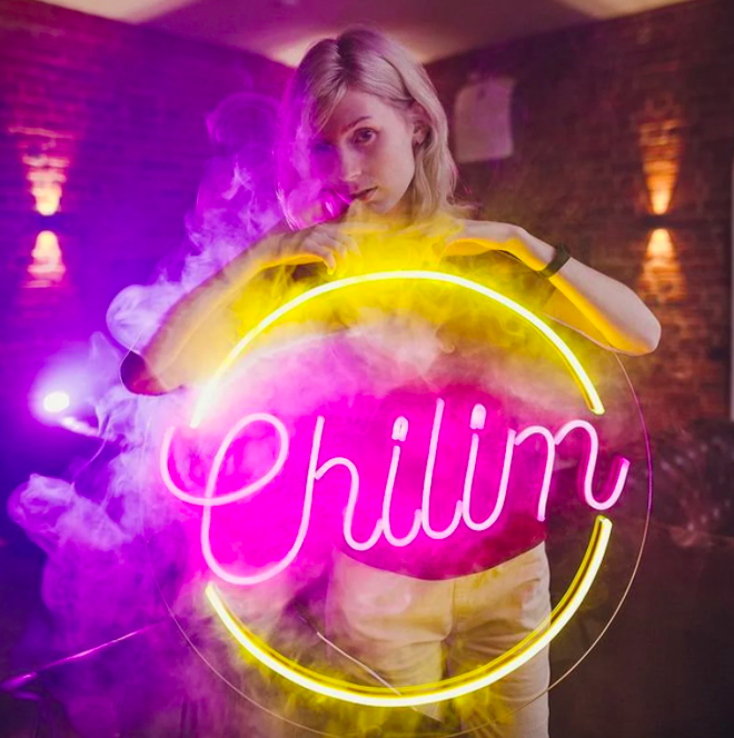 someone holding up a circular neon sign that says chillin&#x27;