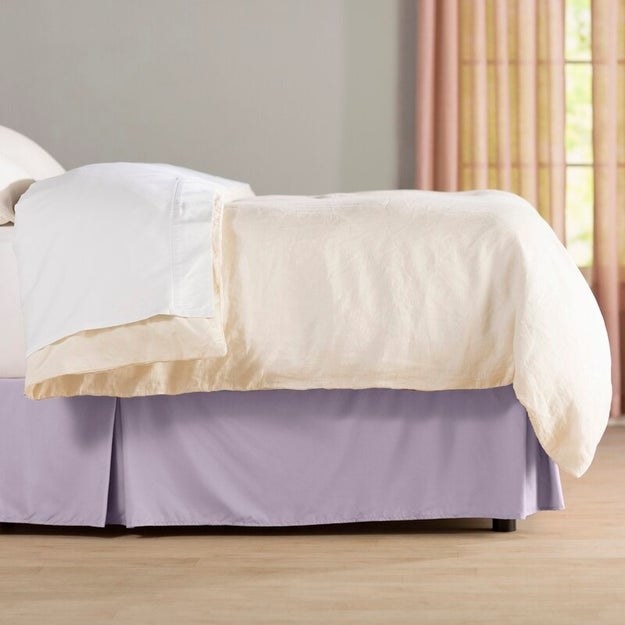 A purple bed skirt on a white bed