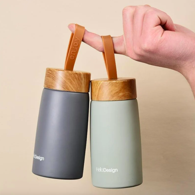 someone dangling a pair of insulated coffee mugs from their finger by the silicone cap strap