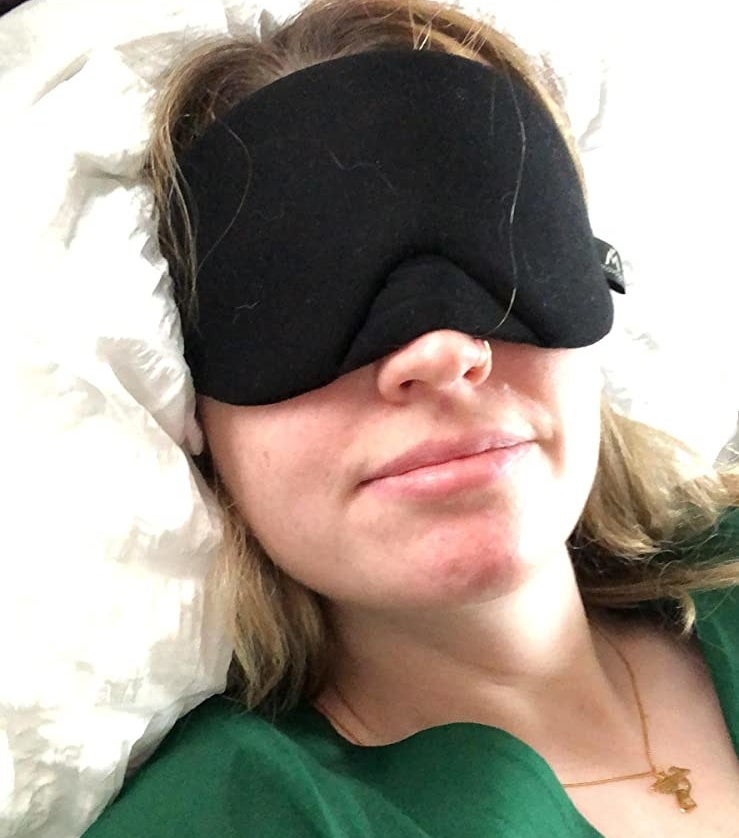 reviewer wearing the black sleep mask in bed