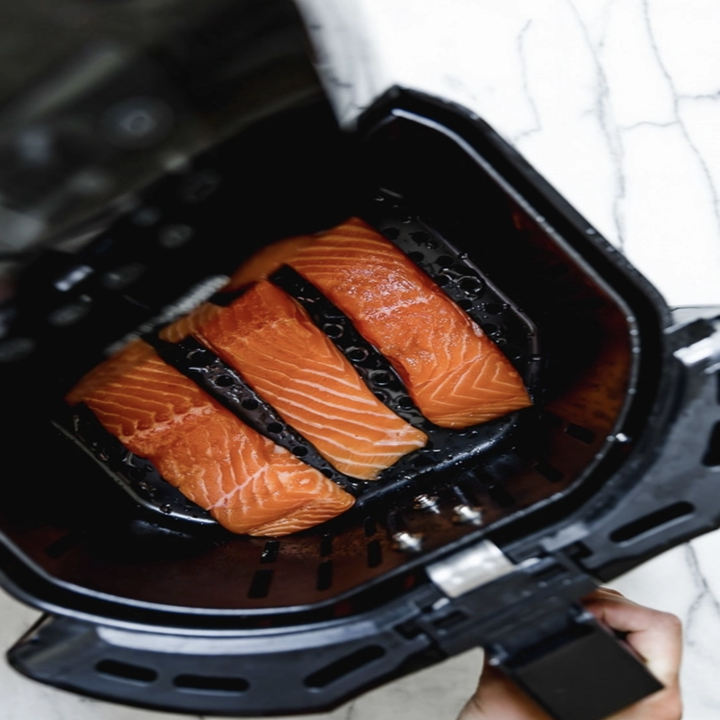 Three pieces of salmon in an air fryer basket.