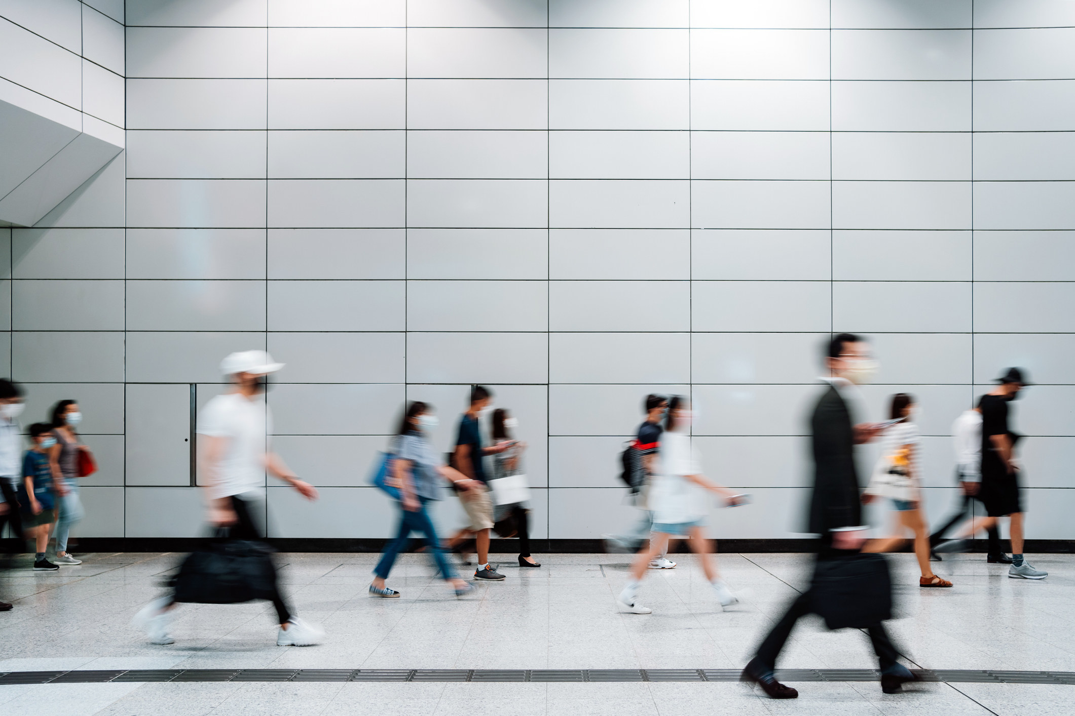 A crowd of people in the subway, blurred as they walk by