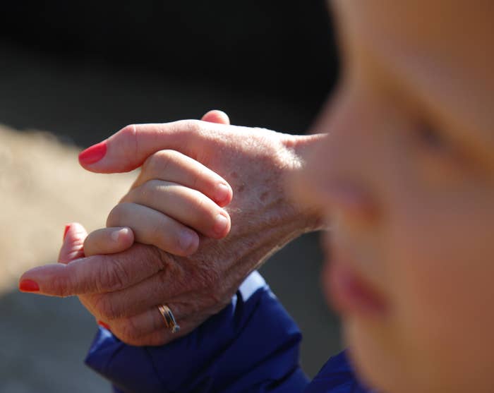 Photo of a young kid holding an older woman&#x27;s hand