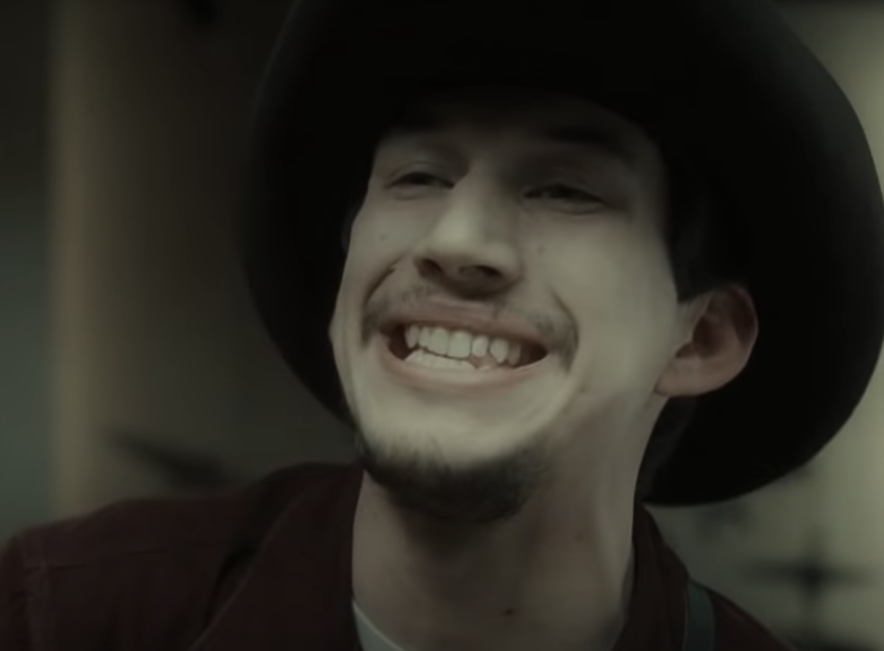 Adam Driver in the film smiling with his teeth