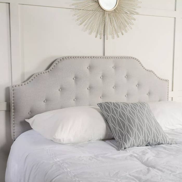 Gray tufted headboard behind bed