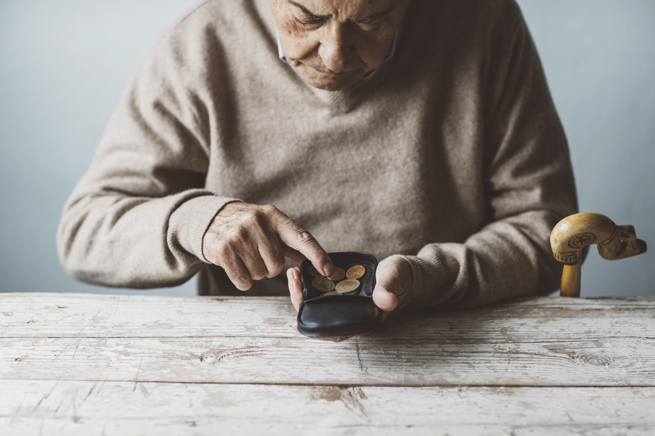 An older person counts coins in their wallet