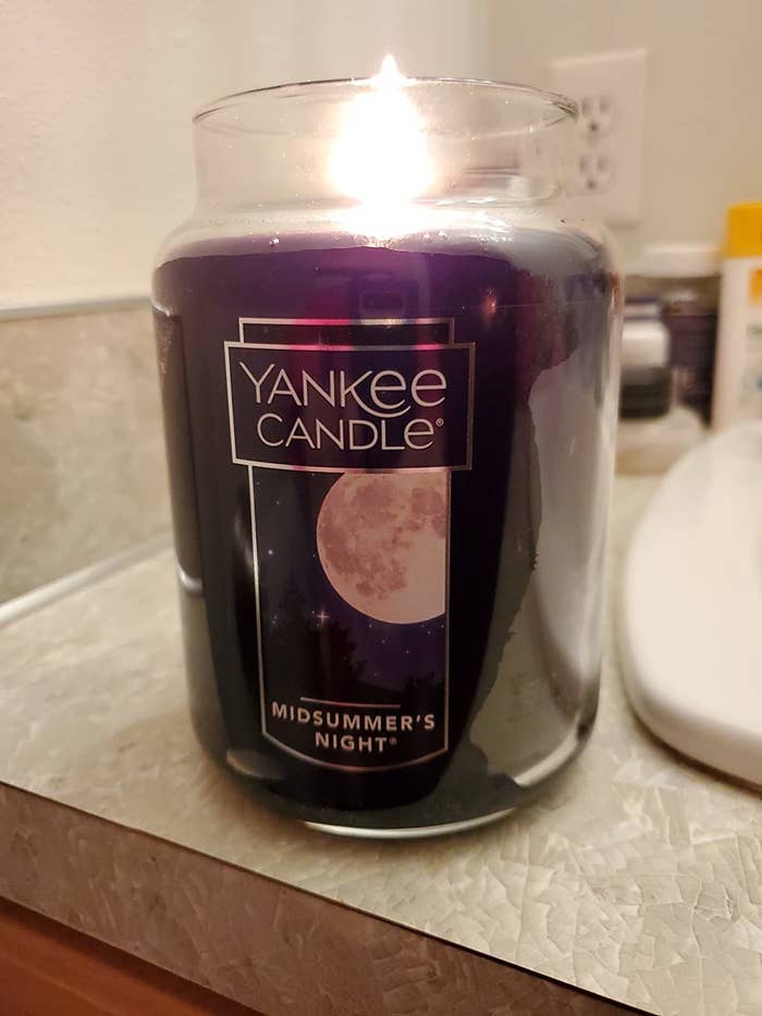 Reviewer's candle is shown lit on a bathroom countertop