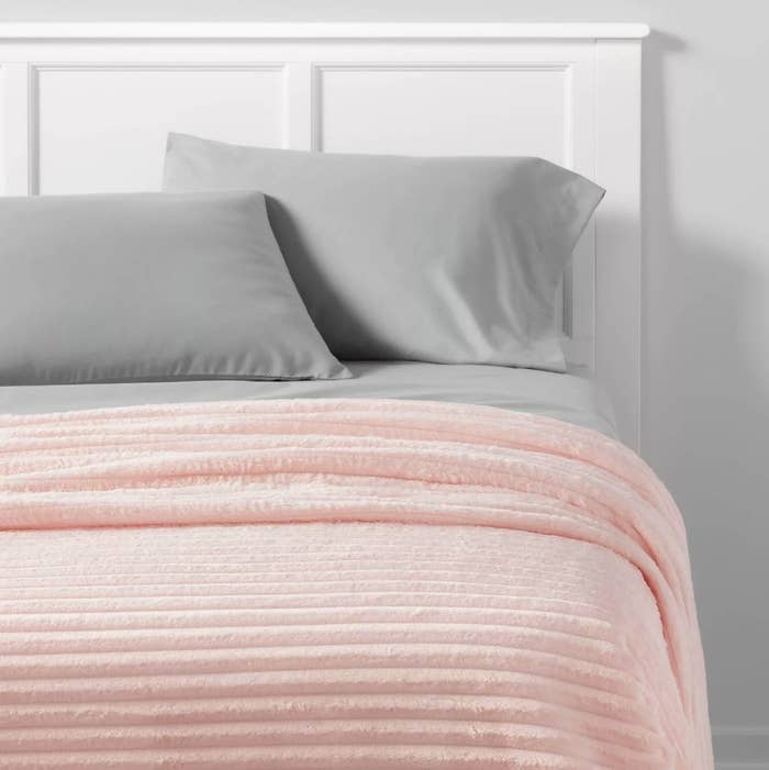 Pink ribbed blanket on bed with gray sheets