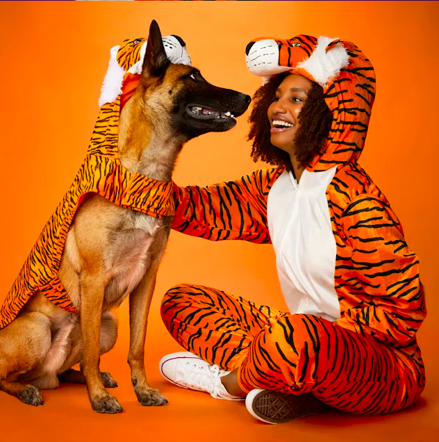 a model and dog both wearing a tiger onesie