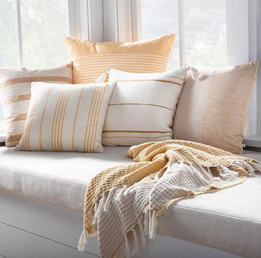Yellow and white fringe throw blanket on couch next to matching pillows