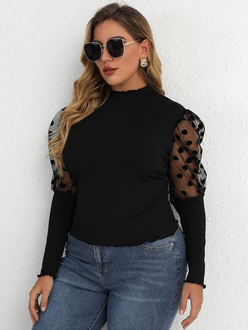 model wearing the black top with polka dot puff sleeves at the top and the bottom half of the sleeve solid black