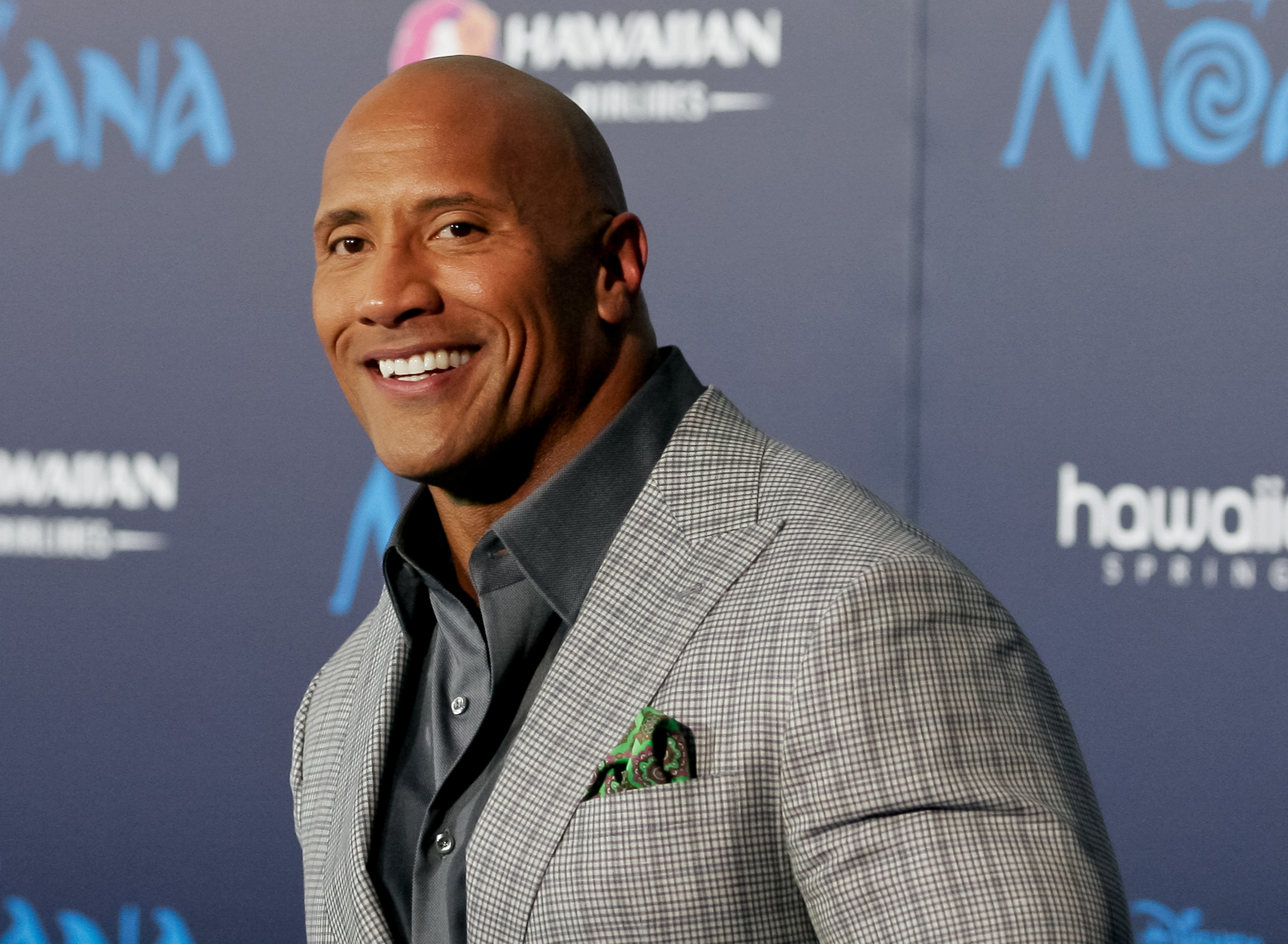 Dwayne Johnson smiles at a movie premiere.