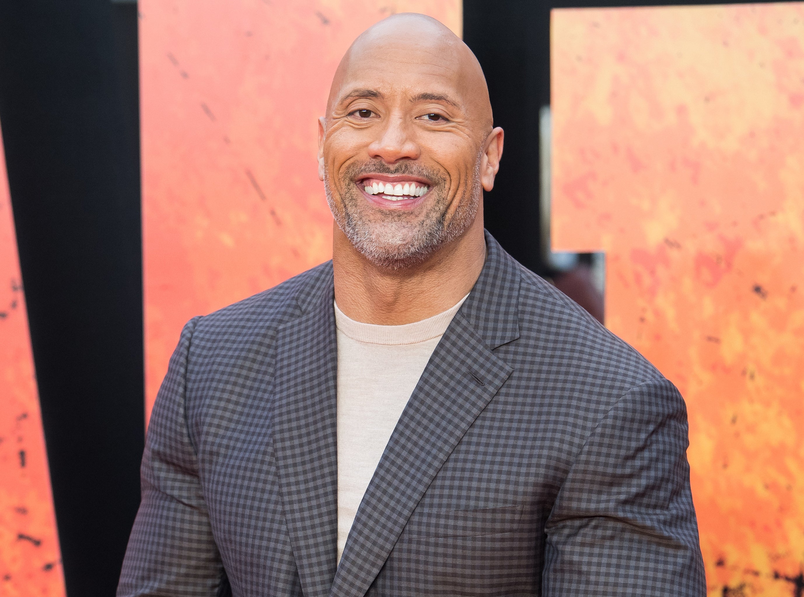 Dwayne Johnson smiles as he walks the red carpet.