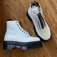 A reviewer showing a pair of newly-opened white platform boots laying on the floor