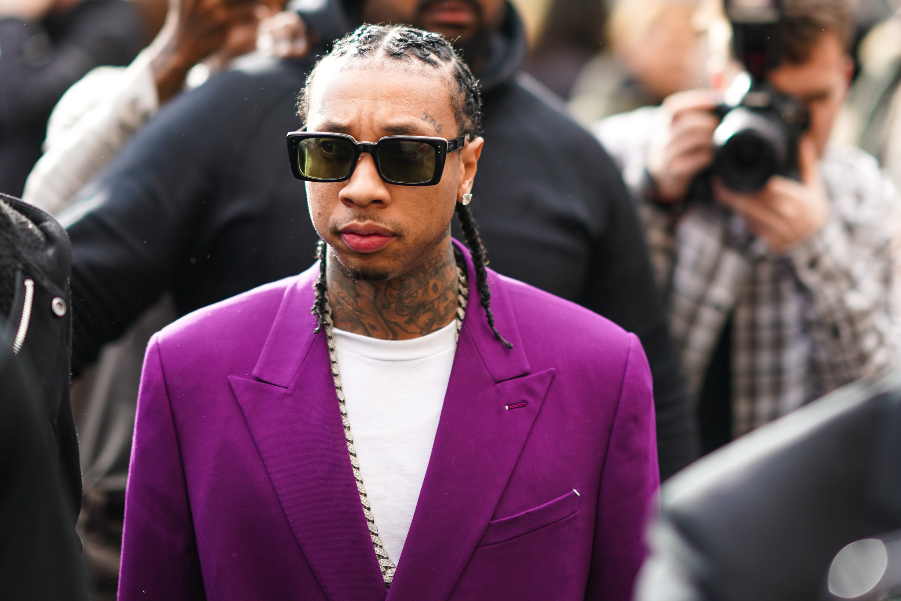 Tyga looks serious while standing in a crowd of photographers