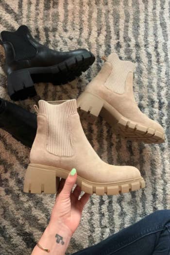 A person holding the beige Chelsea boots