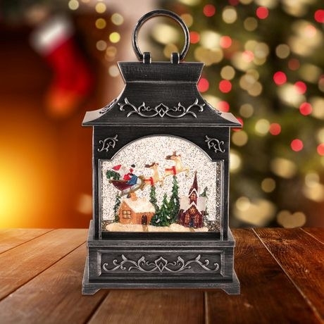 an ornament depicting Santa with his reindeer flying over a house
