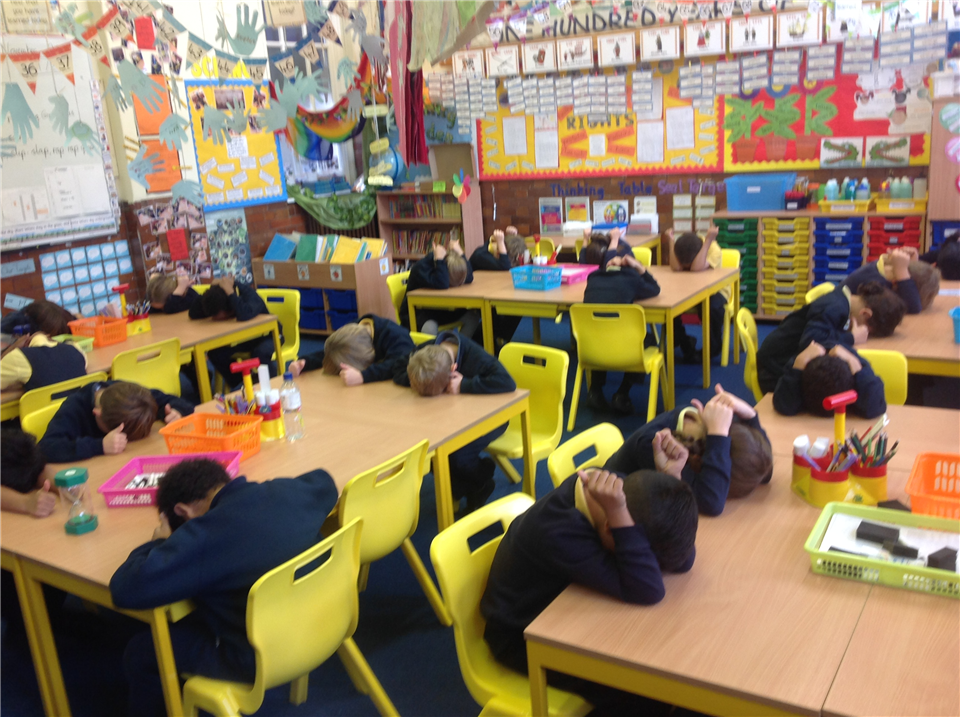 Students in a classroom playing heads down, thumbs up