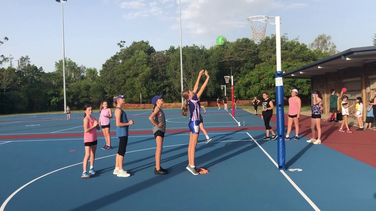 A group of children playing Golden Child on a netball court