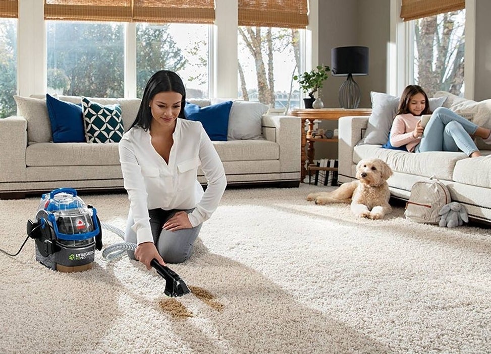 model holding portable vacuum with a dog and child sitting nearby