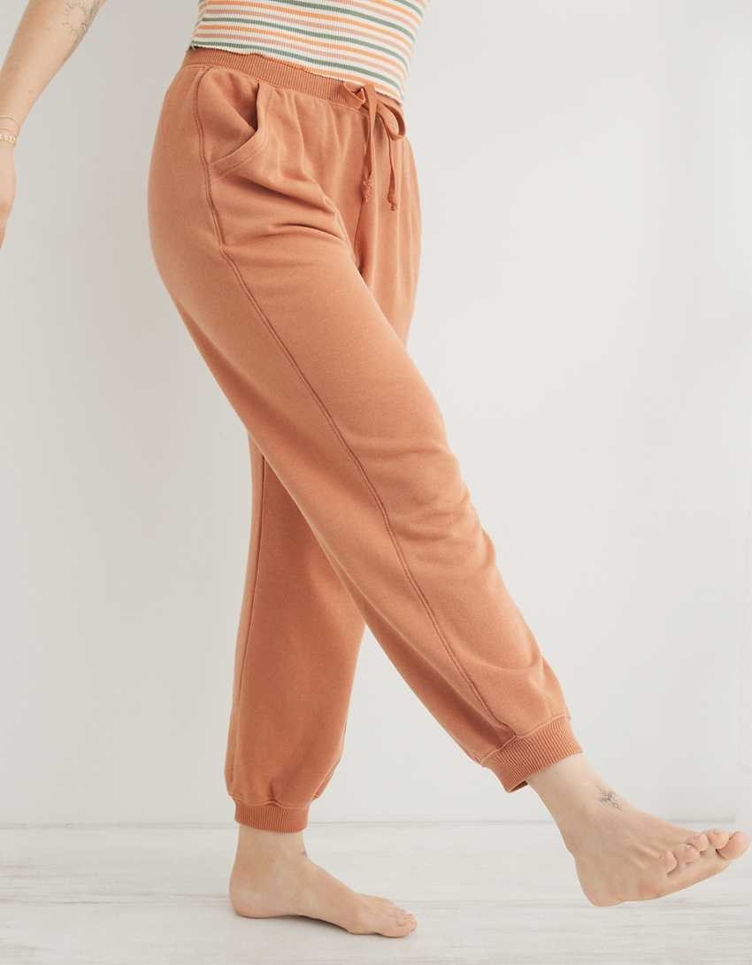 model wearing the sweats in orange with a striped top and one leg up in the air