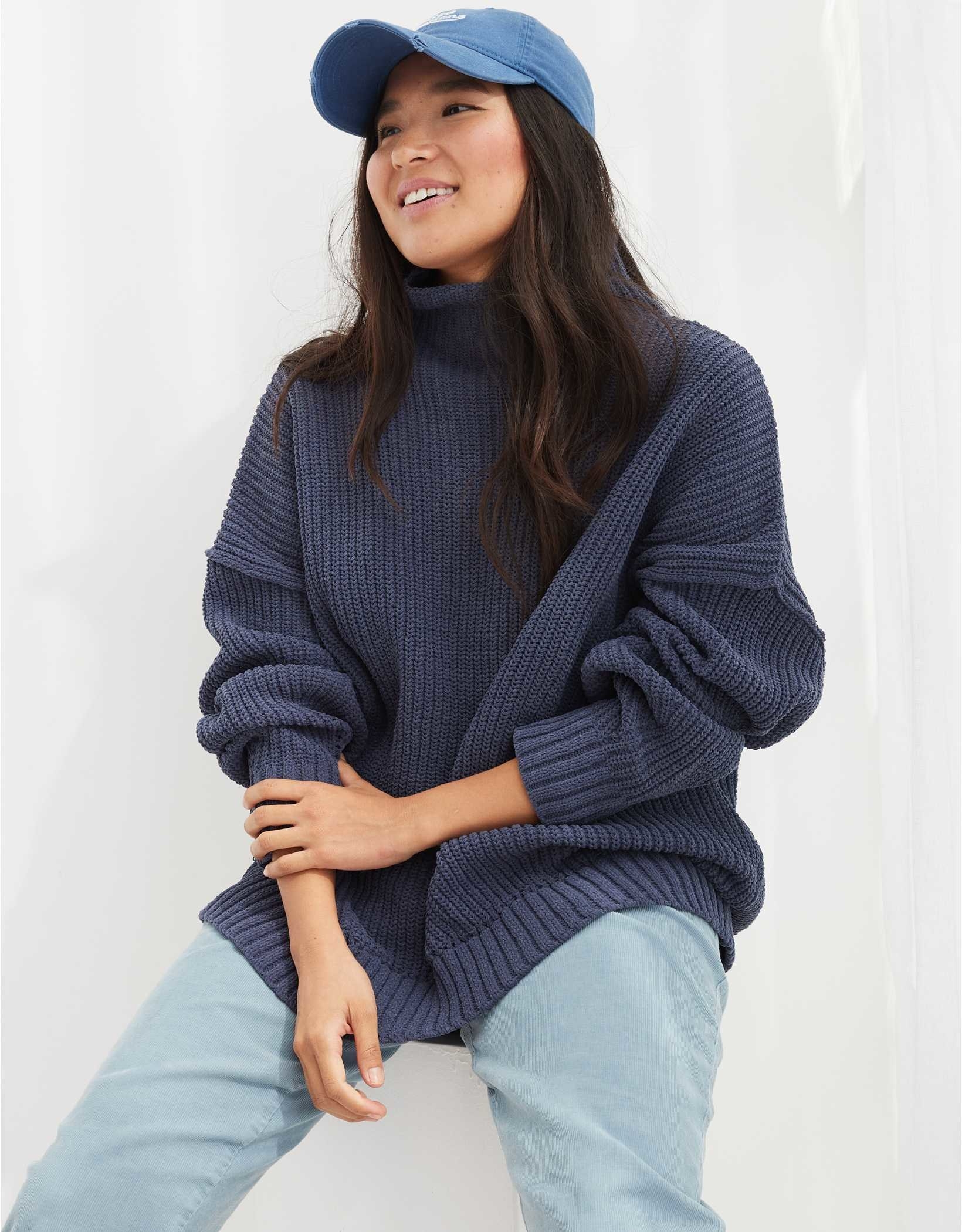 model wearing the sweater in navy blue with light blue pants and a blue hat