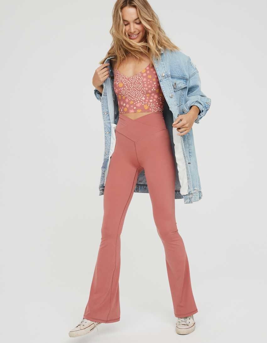 model wearing the flare leggings in pink with white converse, pink and white top and a denim overcoat