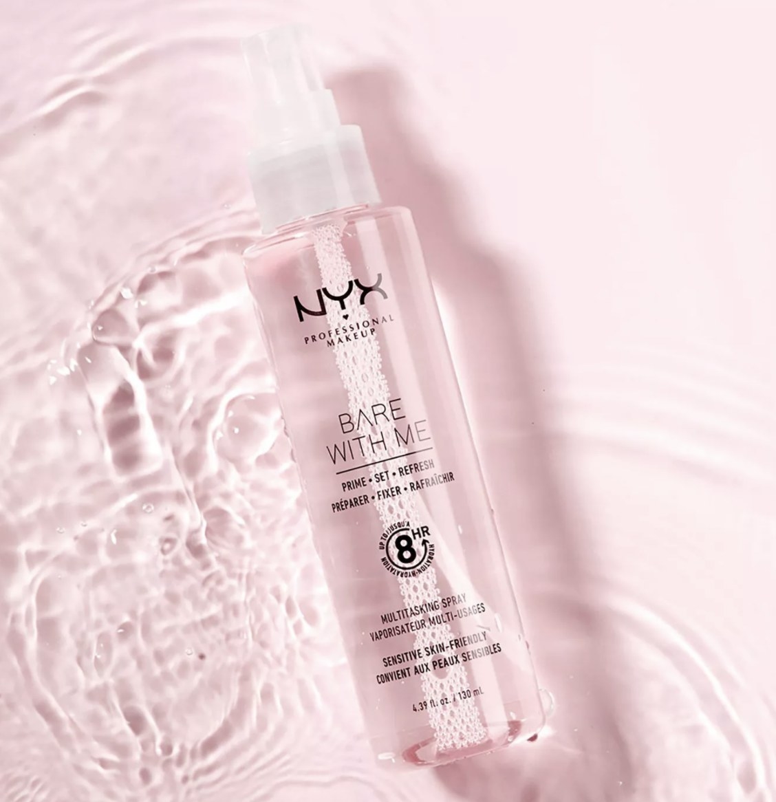 The light pink bottle says &quot;NYX PROFESSIONAL MAKEUP&quot; and &quot;BARE WITH ME&quot; and is laid against liquid on a light pink background